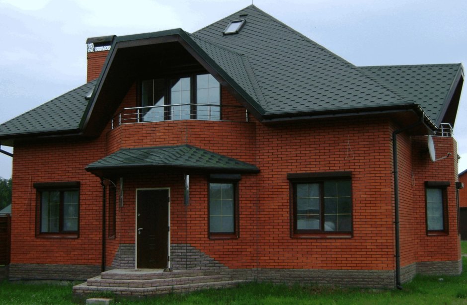 Красный кирпичный дом с зеленой крышей